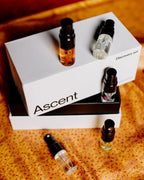 Ascent perfume discovery set with four bottles on a textured surface