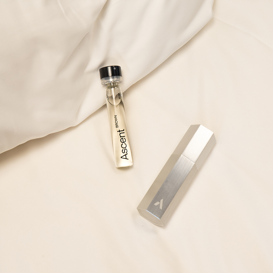 The Ascent aluminium case next to a 20 ml extrait refill on linen