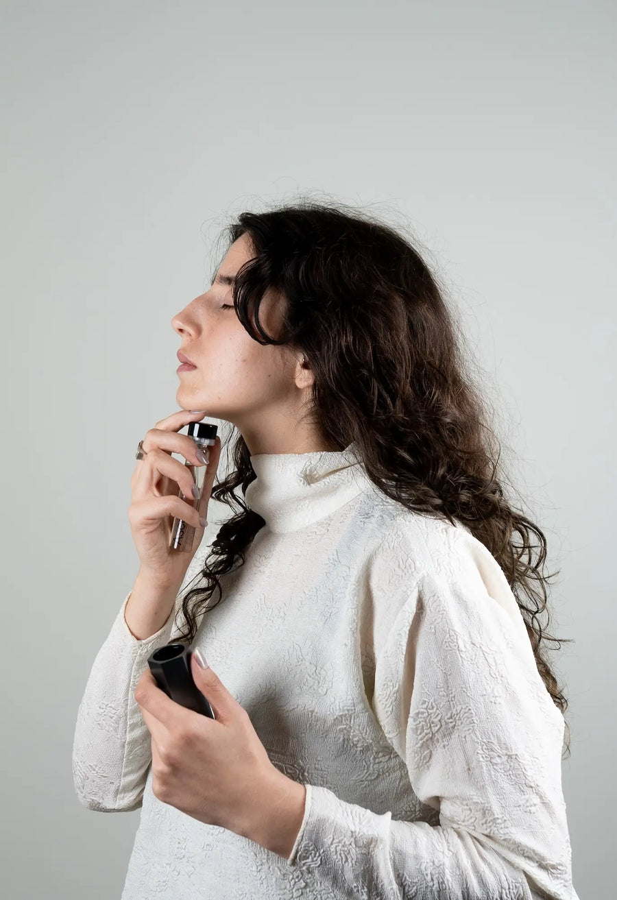 A woman spraying Ascent extrait on her neck