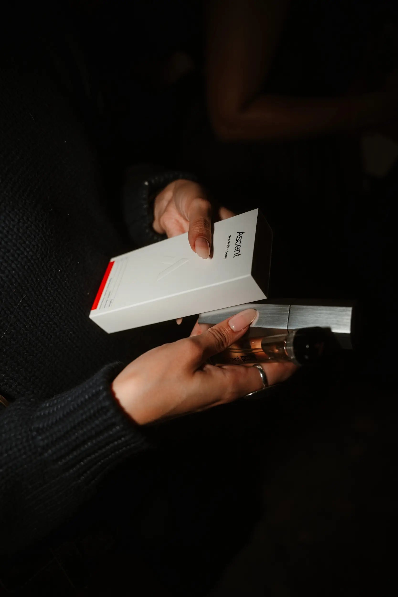 Person holding an ascent box with red accents in a dark setting