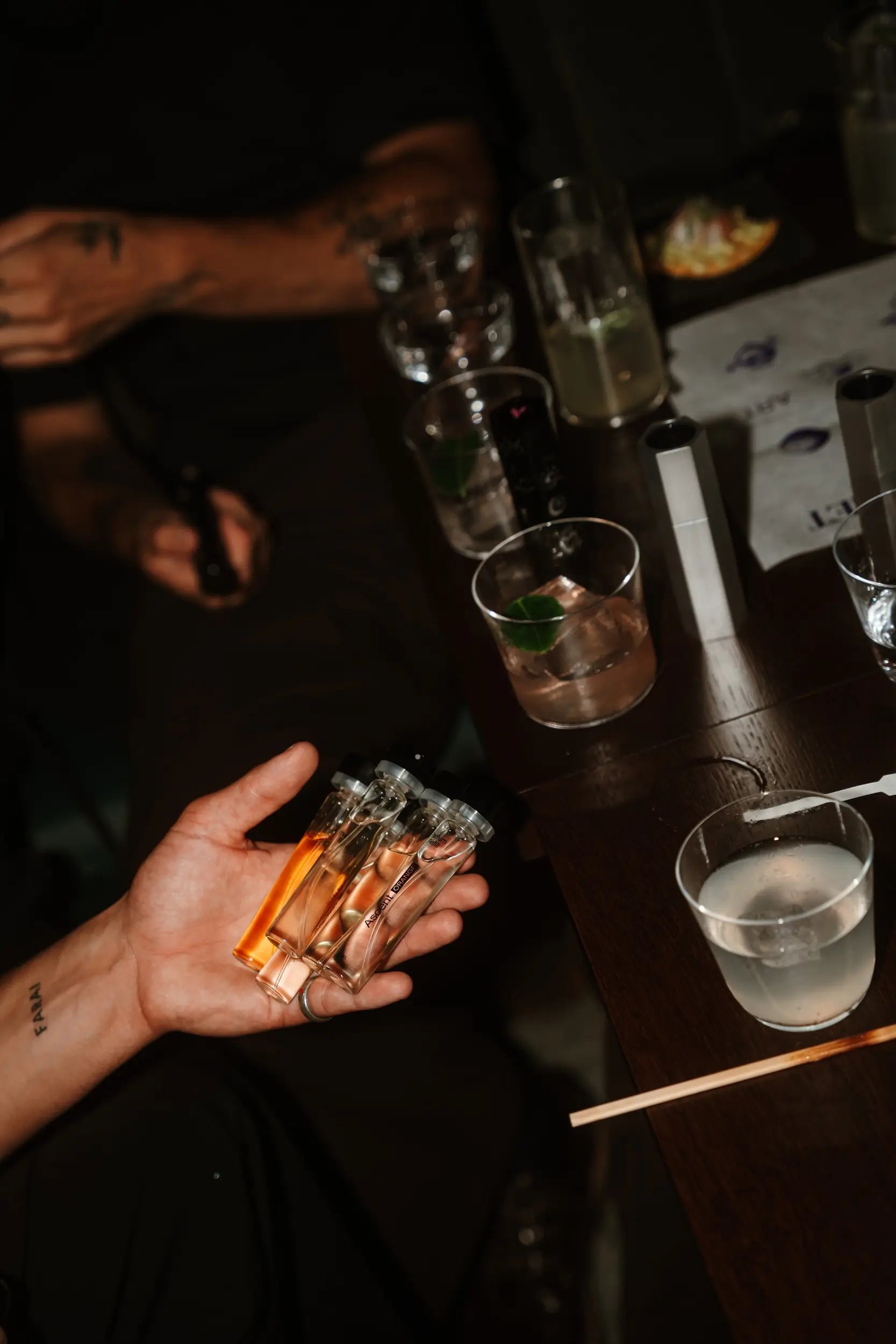 Hand holding lit candles with a bar counter and drinks in the background