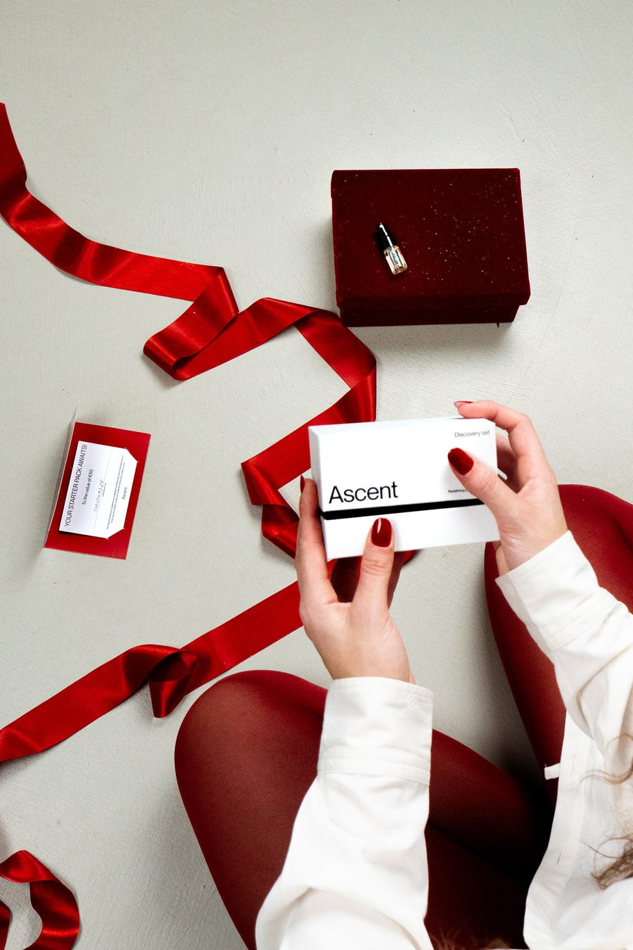 Hands unwrapping an Ascent gift tied with red ribbon
